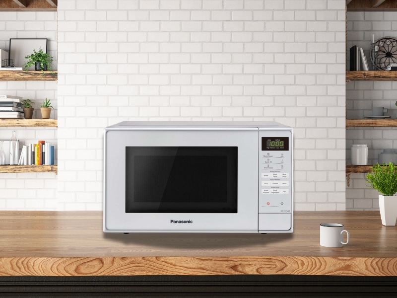 Panasonic microwave convection oven on a wooden kitchen bench with shelves and brick wall background.