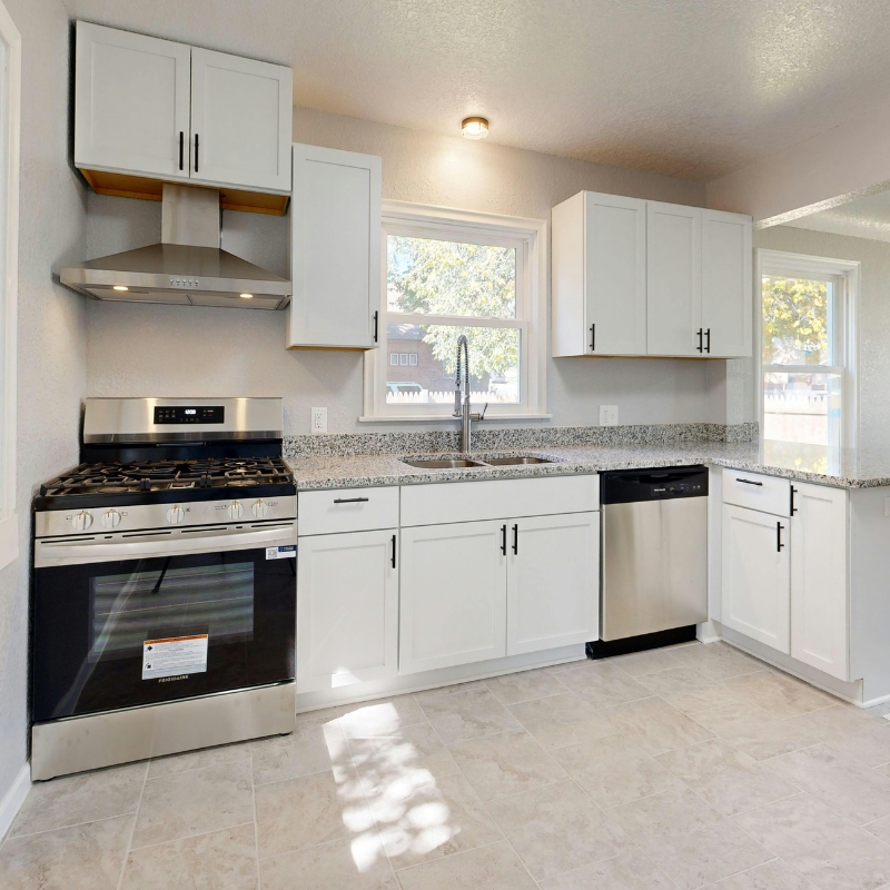Modern white kitchen appliances including stainless steel oven, gas cooktop, rangehood and dishwasher.